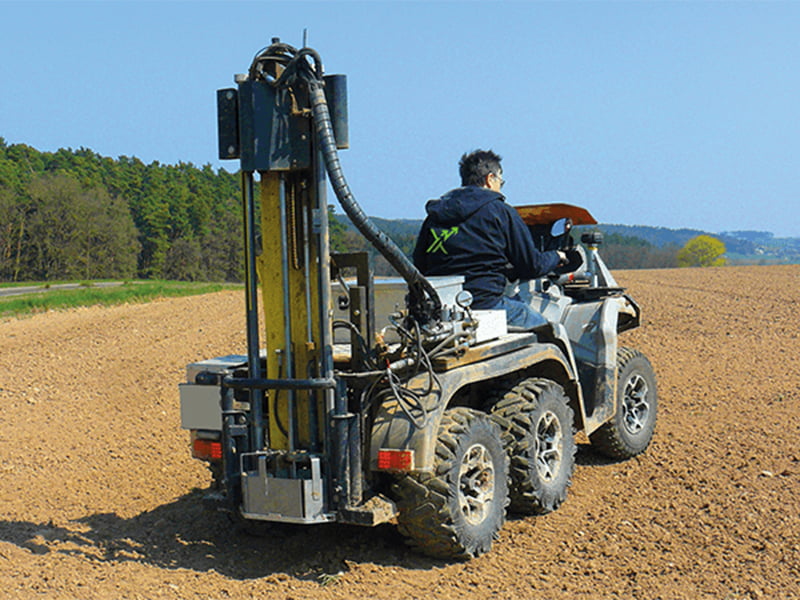 Mann befindet sich mit einem Bodenproben Ausitztruck auf dem Feld.