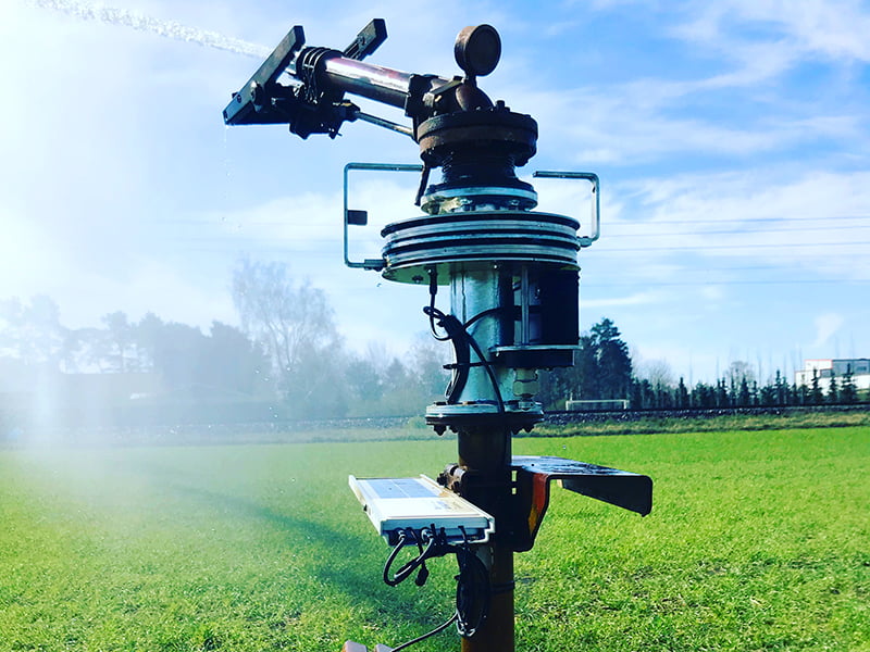 Spritzdüse einer Beregnungsanlage während diese ein Feld bewässert.